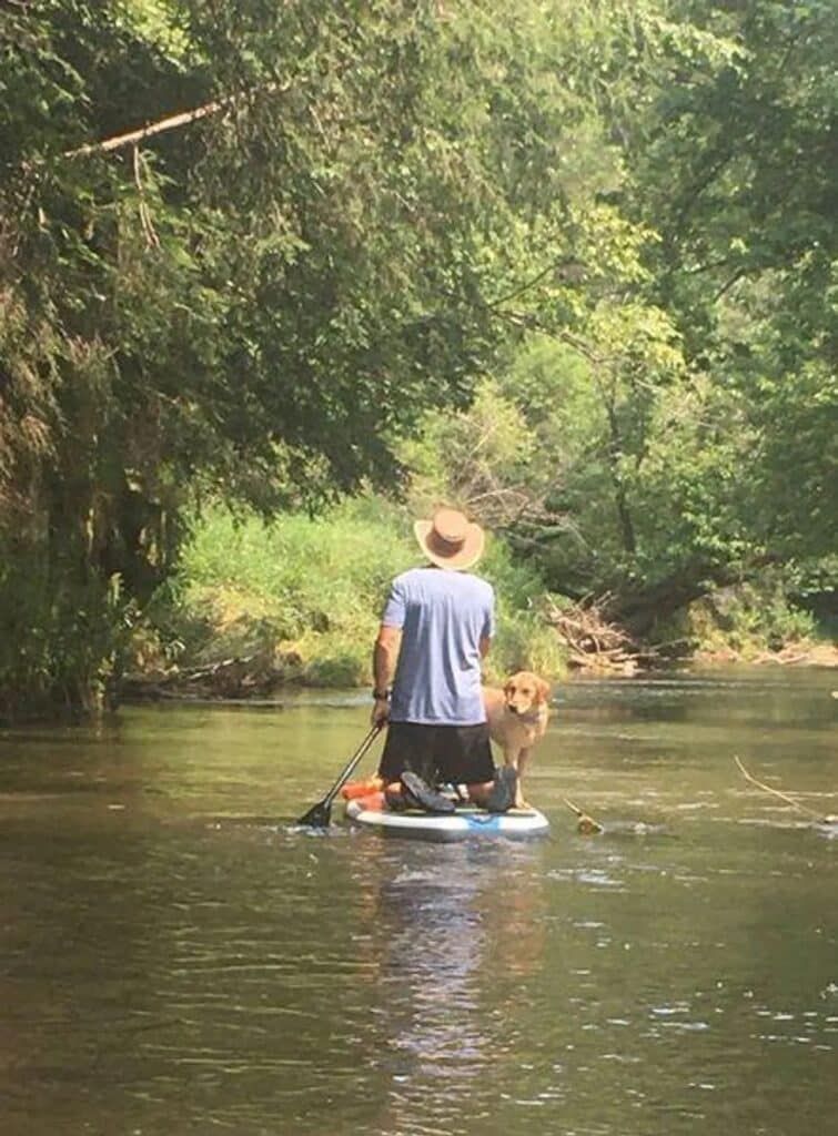 The author paddelboarding with his yellow labrador retriever on a river in Colorado